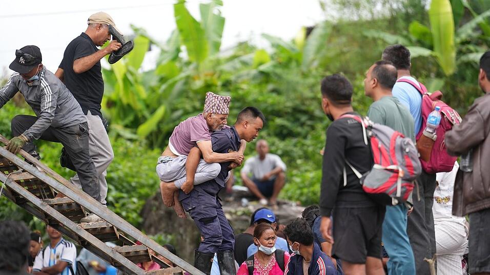 Ein Mann wird im Katastrophengebiet in Nepal von einem Polizisten auf dem Rücken getragen. Ein Mann wird im Katastrophengebiet in Nepal von einem Polizisten auf dem Rücken getragen.