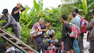 Ein Mann wird im Katastrophengebiet in Nepal von einem Polizisten auf dem Rücken getragen. Ein Mann wird im Katastrophengebiet in Nepal von einem Polizisten auf dem Rücken getragen.