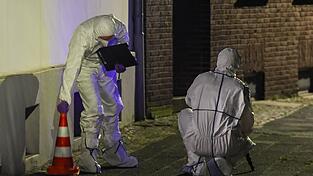 Beamte der Spurensicherung in Spurensicherungsanzügen begutachten den Tatort. Beamte der Spurensicherung in Spurensicherungsanzügen begutachten den Tatort.