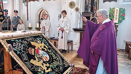 Pfarrer Heinz Prechtl bei der Segnung der restaurierten Fahne.