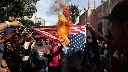 Venezolaner verbrennen in der Hauptstadt Caracas eine US-Flagge, nachdem die US-Angriffe und die Gefangennahme des venezolanischen Staatschefs Maduro bekannt gegeben wurden.