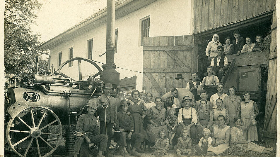 Bewegliche Dampfmaschinen waren f&uuml;r die Entwicklung der Landwirtschaft von gro&szlig;er Bedeutung. Hier pr&auml;sentiert sich eine Gruppe von rund 20 Erntehelfern mit Kindern und Maschinisten stolz neben der Maschine. Das Foto wurde vom Landschaftsfotografen Georg Bayerl aus &Ouml;tzing bei Tiefenbach (Landkreis Passau) aufgenommen.
