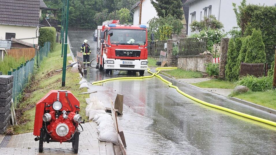Feuerwehrleute haben auf einer Dorfstra&szlig;e nach heftigen Regenf&auml;llen Pumpen aufgestellt.