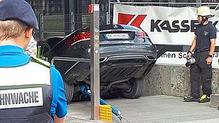 Einsatzkräfte der Feuerwehr betrachten in München das Auto eines französischen Ehepaars, das die Treppe zur U-Bahn hinuntergefahren ist.