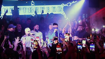 Während alle Handys auf ihn gerichtet sind, verbirgt Haftbefehl sein Gesicht unter einem Tuch.