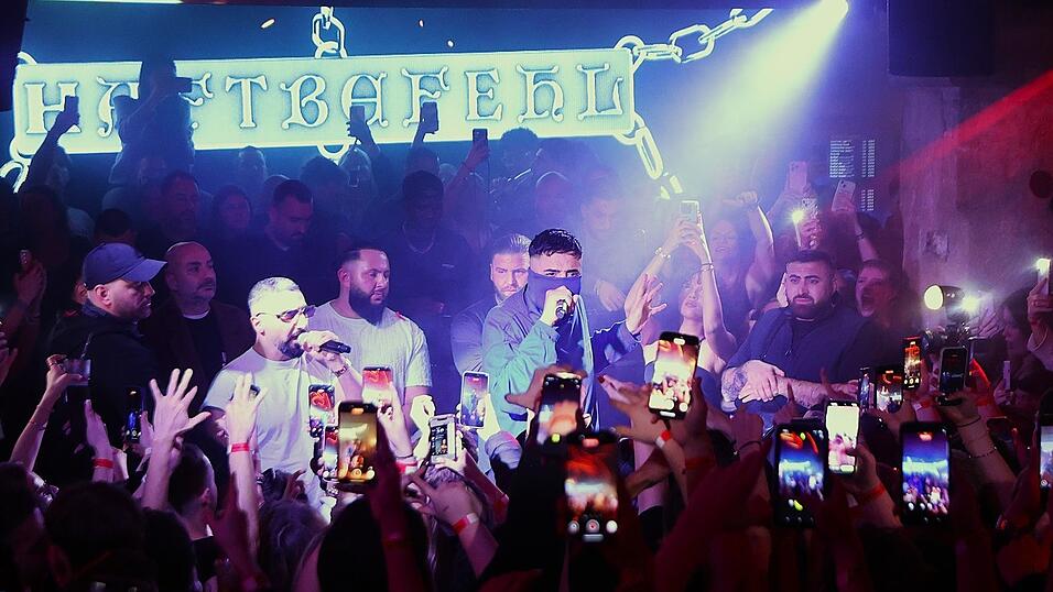 Während alle Handys auf ihn gerichtet sind, verbirgt Haftbefehl sein Gesicht unter einem Tuch. Während alle Handys auf ihn gerichtet sind, verbirgt Haftbefehl sein Gesicht unter einem Tuch.