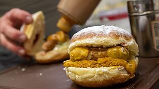 Bäckermeister Florian Perkmann bereitet einen Wurst-Krapfen in seiner Bäckerei zu. Bäckermeister Florian Perkmann bereitet einen Wurst-Krapfen in seiner Bäckerei zu.