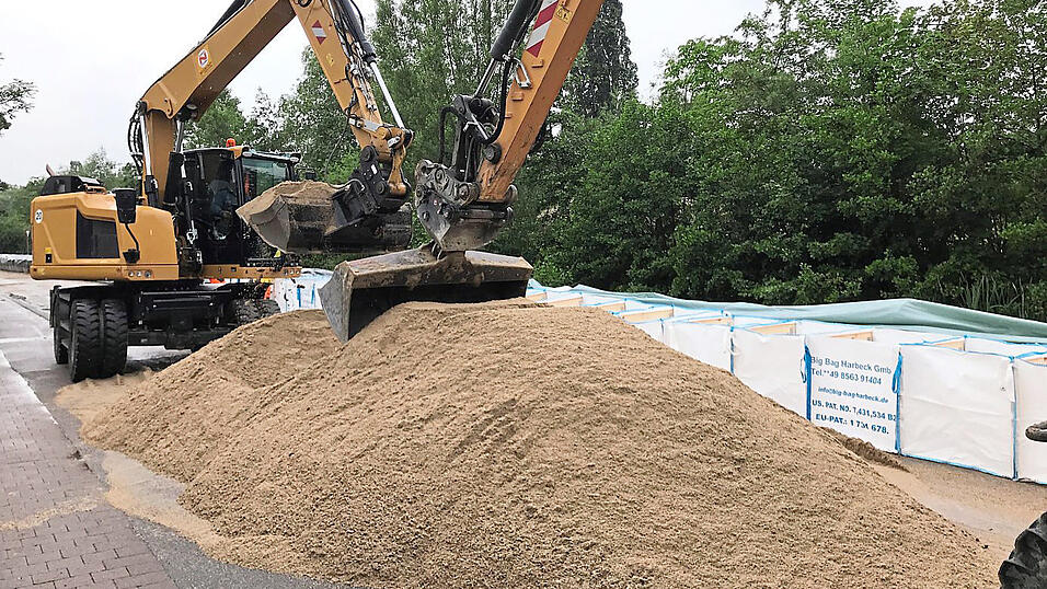 Mit großen Lastwagen wurden Berge von Sand am Schanzlweg für die Befüllung der 'Big Bags' angeliefert und von Baggern verteilt. Mit großen Lastwagen wurden Berge von Sand am Schanzlweg für die Befüllung der 'Big Bags' angeliefert und von Baggern verteilt.