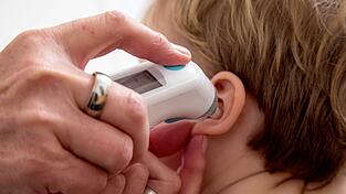 Bei einem Kind wird die Temperatur gemessen. In mehreren europäischen Ländern sind bei Kindern ungewöhnlich schwere Erkrankungen festgestellt worden, darunter in Deutschland.