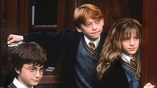 Voller Erwartung stehen die Zauberlehrlinge Harry Potter (Daniel Radcliffe, l.), Ron Weasley (Rupert Grint) und Hermine Granger (Emma Watson) im Kinofilm 'Harry Potter und der Stein der Weisen' an der T&uuml;r zur Hogwarts-Schule f&uuml;r Zauberkunst (Szenenfoto).
