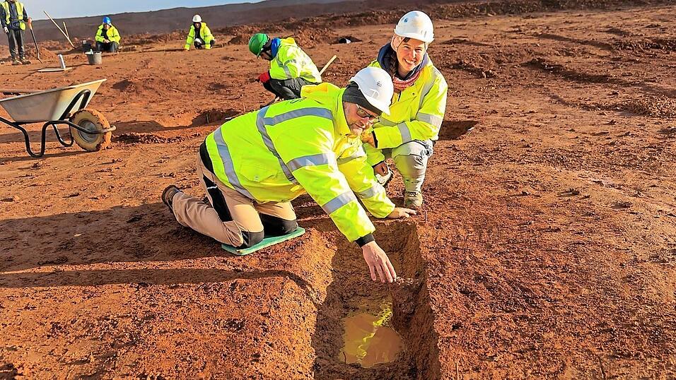 Ingrid Tamerl-Seiler (r.) und Michael Seiler zeigen einen Stein in einem der Pfostenlöcher. Mit ihm haben die Menschen in der Bronzezeit den Pfosten verkeilt. Ingrid Tamerl-Seiler (r.) und Michael Seiler zeigen einen Stein in einem der Pfostenlöcher. Mit ihm haben die Menschen in der Bronzezeit den Pfosten verkeilt.