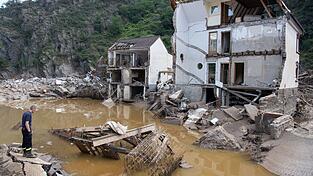 Ein Feuerwehrmann steht nach dem Hochwasser im Ahrtal 2021 vor einem v&ouml;llig zerst&ouml;rten Haus: Angesichts zunehmender Extremwetter-Ereignisse wird &uuml;ber eine Versicherungspflicht diskutiert.