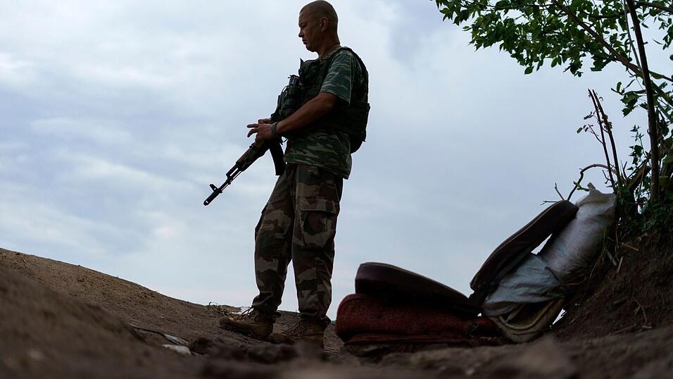 Ein ukrainischer Soldat hält in der Region Donezk Wache vor seinem Zelt.