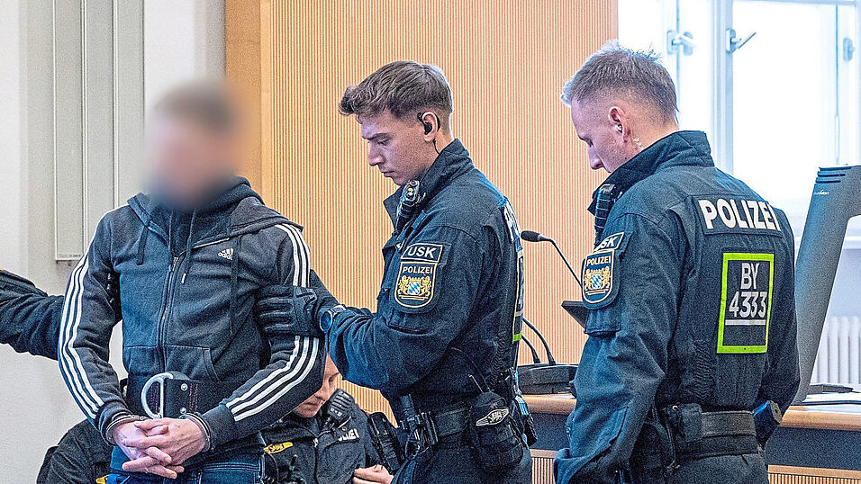 Die Finger ineinander verschr&auml;nkt, die H&auml;nde in Handschellen an einem Bauchgurt befestigt. Unter hohen Sicherheitsvorkehrungen bringen Polizisten einen der Angeklagten in den Verhandlungssaal.