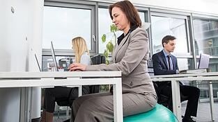 Auf dem Ball sitzen trainiert die tiefliegende Rückenmuskulatur.