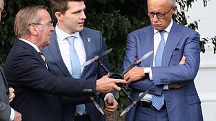 Verteidigungsminister Boris Pistorius (l.) reicht Bundeskanzler Friedrich Merz (r.) eine Drohne: Was in der Autoindustrie an B&ouml;rsenwert und Arbeitspl&auml;tzen verloren geht, soll in der deutschen R&uuml;stungsindustrie wenigstens zum Teil ausgeglichen werden, das ist das Signal, das von der Regierung Merz ausgeht.