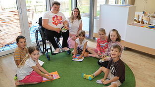 Kathrin Probst und die Leiterin der Kindertagesst&auml;tte Theresa Strohmeier (Mitte) mit Vorschulkindern, die Schuhb&auml;nder binden &uuml;ben.