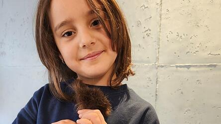 Lena Aigner zeigt stolz ihren abgeschnittenen Zopf.