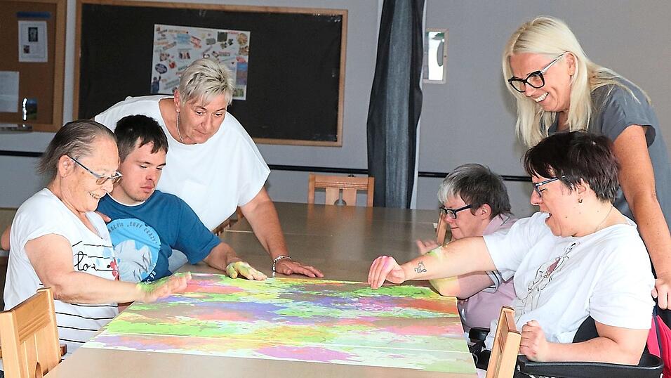 Teamleiterin Sabine Mehrer (rechts) und Mitarbeiterin Alexandra Ertl bei Tover-Spielen mit Besch&auml;ftigten. Die Tovertafel, ein an der Decke verankerter Lichtprojektor, der Spiele auf einen Tisch projiziert, kommt bei den Besch&auml;ftigten bestens an.