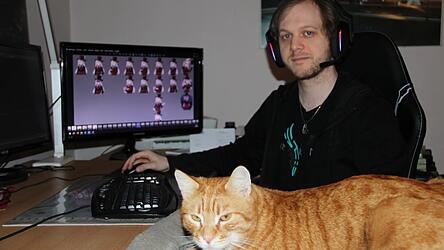 Maximilian Abstreiter mit Kater Louis an seinem Arbeitsplatz