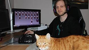 Maximilian Abstreiter mit Kater Louis an seinem Arbeitsplatz