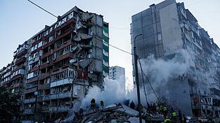 In den Tr&uuml;mmern eines bei einem russischen Angriff teils zerst&ouml;rten Hauses suchen Helfer nach Versch&uuml;tteten.