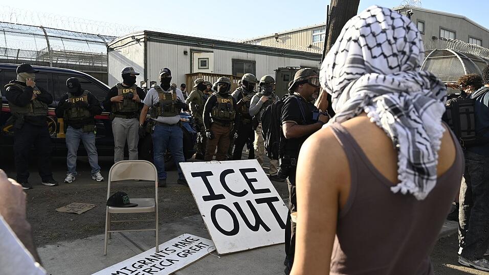 Vor Bundesbeamten der Einwanderungsbehörde ICE haben Demonstrierende ein großes Schild mit der Aufschrift «ICE out» drapiert. Vor Bundesbeamten der Einwanderungsbehörde ICE haben Demonstrierende ein großes Schild mit der Aufschrift «ICE out» drapiert.