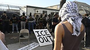 Vor Bundesbeamten der Einwanderungsbeh&ouml;rde ICE haben Demonstrierende ein gro&szlig;es Schild mit der Aufschrift &laquo;ICE out&raquo; drapiert.