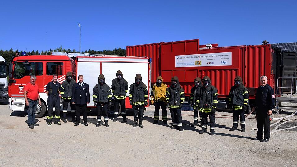 Helmut Mitterbiller, Atemschutz-Kreisbrandmeister Florian Kleber, Gebiets-Kreisbrandmeister Alfred Metzka, die Teilnehmer eines Lehrgangs und Kreisbrandrat Rudi Englbrecht vor dem Brandcontainer und dem Ahamer L&ouml;schfahrzeug.