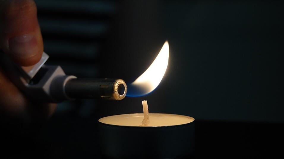 Eine Frau zündet mit einem Feuerzeug ein Teelicht an: Auch in Straubing bleiben Wohnungen dunkel. Eine Frau zündet mit einem Feuerzeug ein Teelicht an: Auch in Straubing bleiben Wohnungen dunkel.