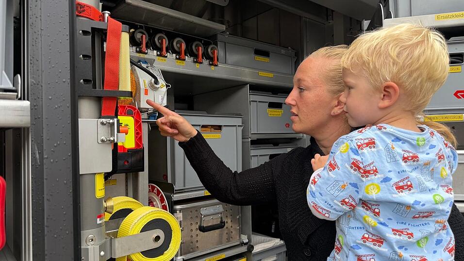 Der kleine Oskar - feuerwehrtechnisch schon perfekt gekleidet - und Mama Anetta begutachteten die Ausr&uuml;stung eines Fahrzeuges.