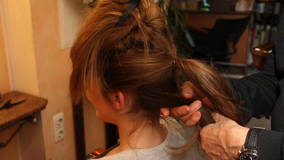 2. Obere Haarpartie am Oberkopf befestigen. Restliche Haare in zwei Pferdeschw&auml;nzen - einen oben, einen unten - festbinden.