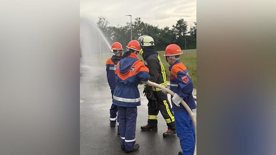 Eine Gruppe mit drei Jugendlichen &uuml;bt zusammen mit ihrem Jugendwarthelfer einen L&ouml;schvorgang.