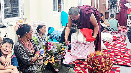 Ein M&ouml;nch aus dem Kloster Kopan in Kathmandu beim Austeilen von Care-Paketen an Frauen mit ihren Kindern, die sich vor der Sturzflut im Trishuli-Tal in Sicherheit bringen konnten.
