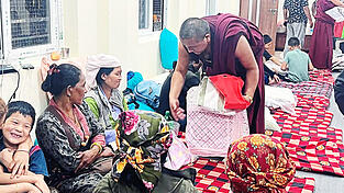Ein M&ouml;nch aus dem Kloster Kopan in Kathmandu beim Austeilen von Care-Paketen an Frauen mit ihren Kindern, die sich vor der Sturzflut im Trishuli-Tal in Sicherheit bringen konnten.