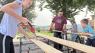 Mit ernsten Mienen sägen die Kinder, unterstützt von erwachsenen Helfern. Mit ernsten Mienen sägen die Kinder, unterstützt von erwachsenen Helfern.