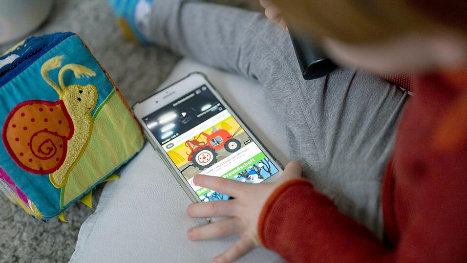 Ein Kleinkind schaut sich Kindervideos auf einem Smartphone an.