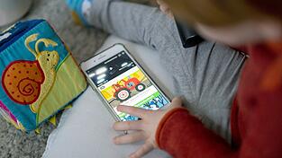 Ein Kleinkind schaut sich Kindervideos auf einem Smartphone an. Ein Kleinkind schaut sich Kindervideos auf einem Smartphone an.