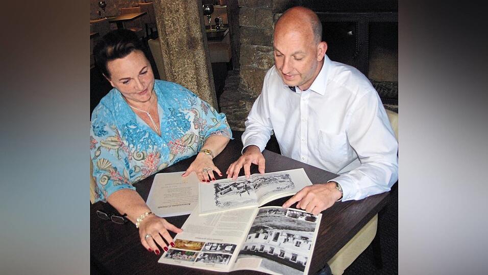 Markus Schmelmer und Carolein Weiß im Gewölbekeller mit (mittig positioniert) dem Heft, in dem Schmelmers Großvater Ludwig die Geschichte des Gutshofs dokumentiert hat. Im Hintergrund Mauern des Ofens, an dem einst die Pferde beschlagen wurden. Markus Schmelmer und Carolein Weiß im Gewölbekeller mit (mittig positioniert) dem Heft, in dem Schmelmers Großvater Ludwig die Geschichte des Gutshofs dokumentiert hat. Im Hintergrund Mauern des Ofens, an dem einst die Pferde beschlagen wurden.
