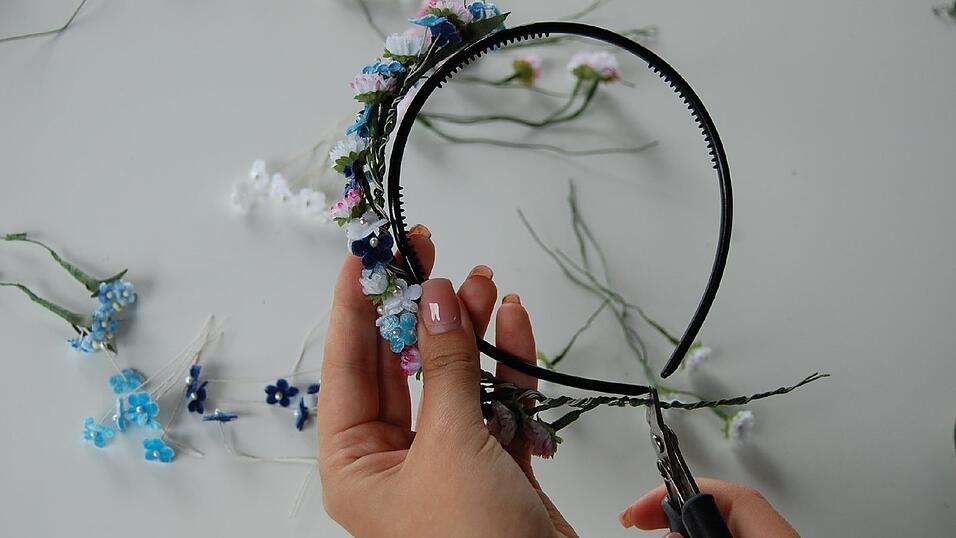 3. Dazwischen das Gebinde immer mal wieder von der Mitte weg an den Haarreif halten, um zu sehen, wie viel noch nötig ist. Die Blümchen soweit binden, so dass nur noch ein bis zwei Zentimeter am Ende frei bleiben, wenn man das Gebinde an den Reif hält. Beim Tragen sollen schließlich nur Blüten und kein Haarreif zu sehen sein. Den Draht dann mit dem Seitenschneider abzwicken, so dass er genauso lang ist wie der Haarreif. 3. Dazwischen das Gebinde immer mal wieder von der Mitte weg an den Haarreif halten, um zu sehen, wie viel noch nötig ist. Die Blümchen soweit binden, so dass nur noch ein bis zwei Zentimeter am Ende frei bleiben, wenn man das Gebinde an den Reif hält. Beim Tragen sollen schließlich nur Blüten und kein Haarreif zu sehen sein. Den Draht dann mit dem Seitenschneider abzwicken, so dass er genauso lang ist wie der Haarreif.