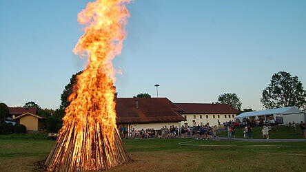 Die lodernden Flammen aus dem Holzturm, im Hintergrund das Partyzelt und und das Feuerwehrger&auml;tehaus