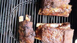 Die geräucherten Beef Ribs auf dem Rost vom Gasgrill. Links erkennt man unter dem Rost die dort platzierte Räucherbox.