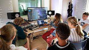 Eine der insgesamt drei Gruppen geht im Regieraum am Studiotisch die bisherigen Aufnahmen und das Musikprojekt in der Digital Audio Workstation (DAW) durch. Eine der insgesamt drei Gruppen geht im Regieraum am Studiotisch die bisherigen Aufnahmen und das Musikprojekt in der Digital Audio Workstation (DAW) durch.