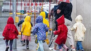 Eine Kindergartengruppe rennt während eines einsetzenden Gewitterregens über den Bürgersteig. Bayern führt verpflichtende Sprachtests im Kindergarten ein. Eine Kindergartengruppe rennt während eines einsetzenden Gewitterregens über den Bürgersteig. Bayern führt verpflichtende Sprachtests im Kindergarten ein.