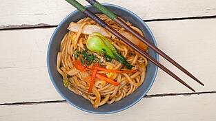 Das sind Ramen-Nudeln in einer Schüssel mit Stäbchen. 'Die Nudeln stammen aus China, sie wurden dann aber von der japanischen Küche eingeführt und übernommen', erklärt Stephanie Wenzel, Verlagsleiterin GU Kochen & Verwöhnen. 'Ramen werden traditionell aus den drei Bestandteilen Weizenmehl, Salz und alkalischem Mineralwasser hergestellt.'