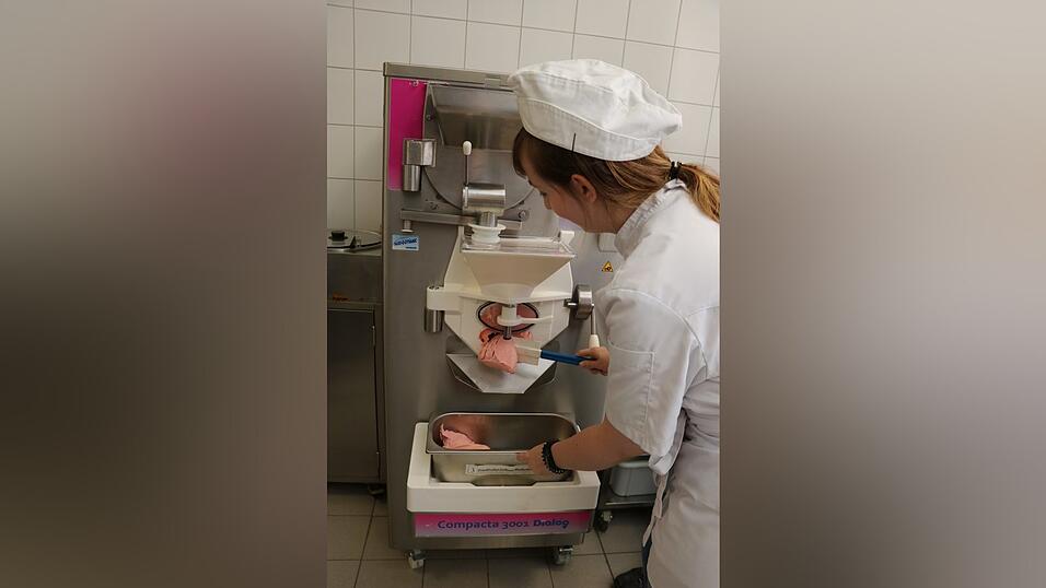 Nach kurzer Zeit quillt aus der Öffnung der Maschine das cremige Eis. Mit schnellen Handbewegungen streift Laura es ab in die Blechwanne. Das Eis ist fertig.