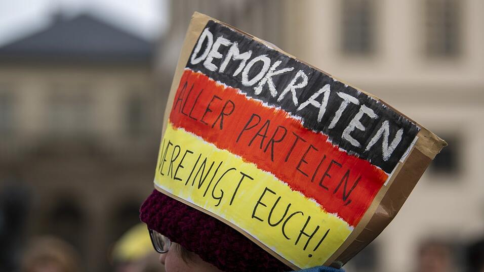 Bei einer Demonstration f&uuml;r Demokratie im vergangenen Jahr in Augsburg tr&auml;gt ein Teilnehmer einen Papphut in Deutschland-Farben und der Aufschrift &bdquo;Demokraten aller Parteien vereinigt Euch&ldquo;.