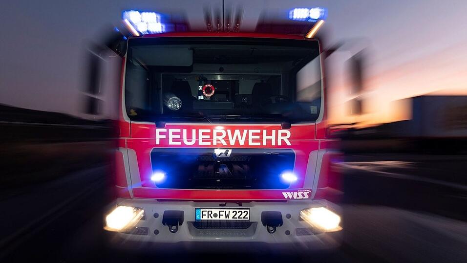 Ein Feuerwehrfahrzeug steht mit eingeschaltetem Blaulicht auf einer Straße. Ein Feuerwehrfahrzeug steht mit eingeschaltetem Blaulicht auf einer Straße.