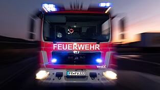 Ein Feuerwehrfahrzeug steht mit eingeschaltetem Blaulicht auf einer Straße. Ein Feuerwehrfahrzeug steht mit eingeschaltetem Blaulicht auf einer Straße.