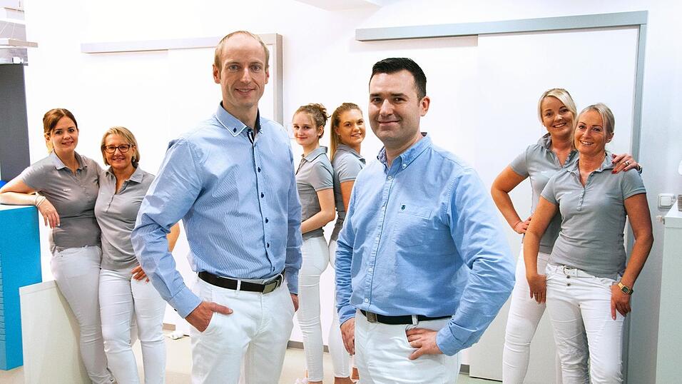 Dr. Michael Igl (links) und Dr. Manuel Kr&auml;mer treten mit ihrer Gemeinschaftspraxis in die Fu&szlig;stapfen von Dr. Hans-J&uuml;rgen Moser. Das angestammte Praxisteam (im Hintergrund) haben sie &uuml;bernommen.